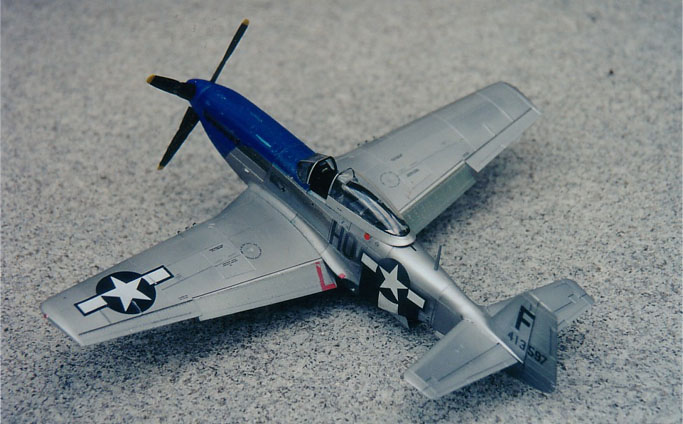 P-51D (early).
This early model P-51D, serial number 413597, HO-F, is called "The Moose" of the 352nd Fighter Group
 
This model is a combination of kits.  The tail of the aircraft is from a P-51B.  The remainder is a P-51D.  I discovered that one cannot simply remove the vertical stabilizer fin strake and have an accurate early model P-51D.  You would also need to rescribe most of the fuselage panel lines aft of the strake.  The P-51B tail assembly panel lines match right up.  I would really love for Tamiya to create an accurate early P-51D model. There are many excellent early P-51Ds to model.  It would fill a very much needed gap for this aircraft.
