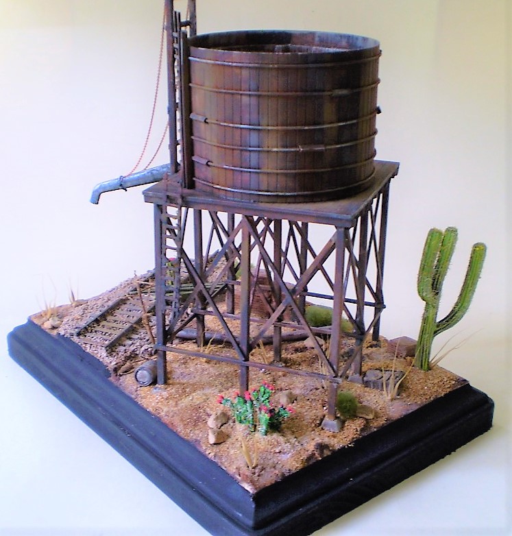 Water Tank (HO Scale)
This is an HO scale, old timey water tank from a forgotten manufacturer. Bits
and bobs from the spares box. The cacti are from Woodland Scenics.

Scale wood was added to the interior of the tank and I replaced the   
metal straps and turnbuckles around the exterior. Most of the dead   
foliage is from my yard.
